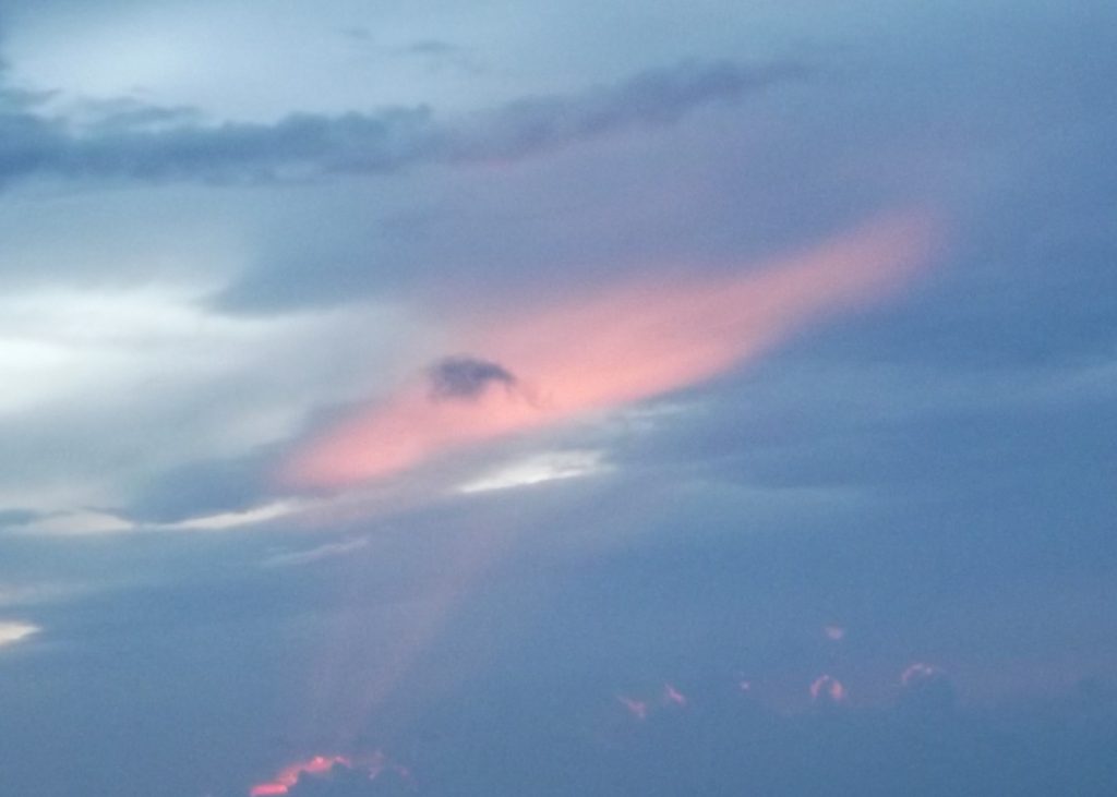 rayo de luz naranja proyectado sobre un cielo completamente cubierto de nubes