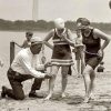 Un hombre midiendo la longitud de la falda de una bañista de principios del siglo XX