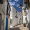 Una calle de un pueblo de fachadas blancas y puertas azules